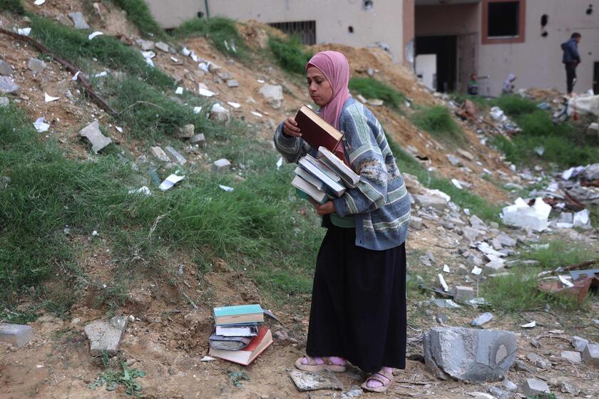 Palestinesi sfollati raccolgono libri dall'università distrutta per bruciarli e cucinare cibo