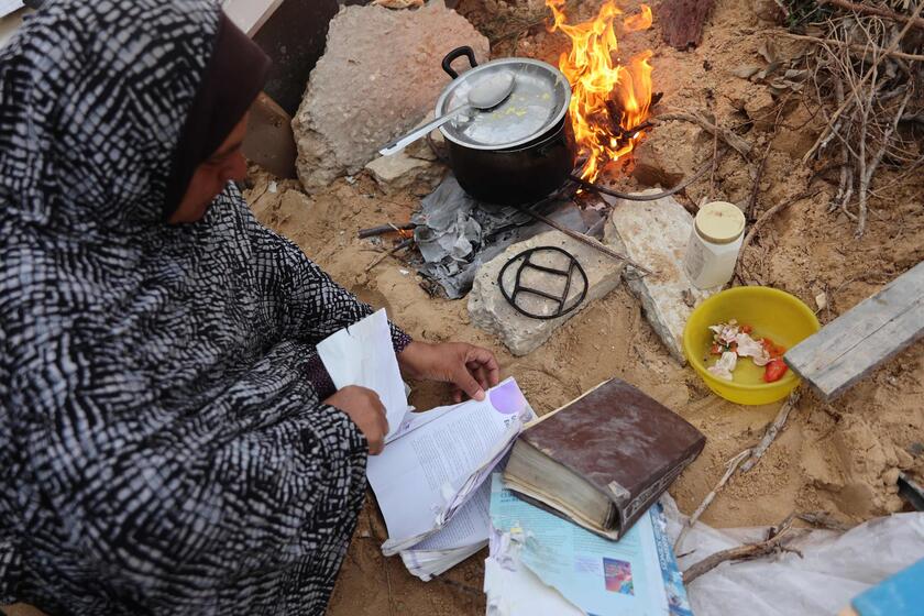 Palestinesi sfollati raccolgono libri dall'università distrutta per bruciarli e cucinare cibo