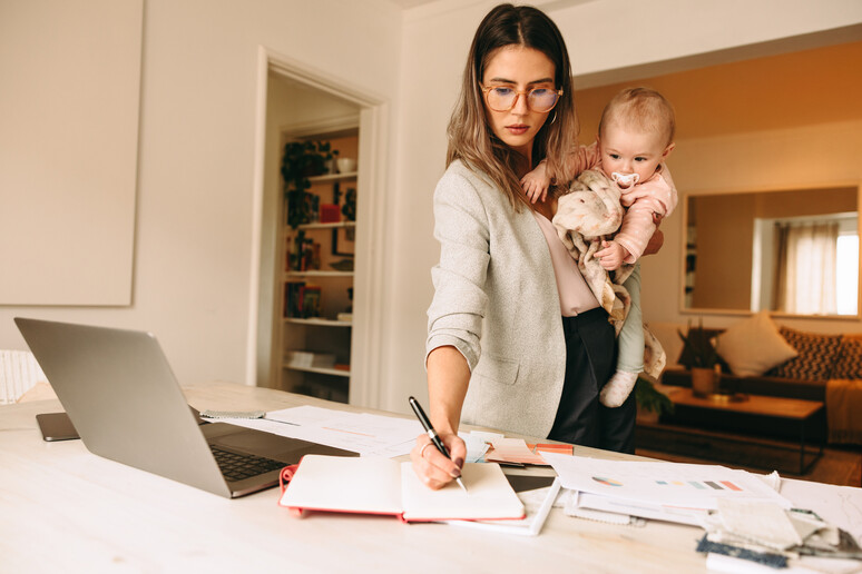 Una mamma con un bambino piccolo a lavoro da casa foto iStock. - RIPRODUZIONE RISERVATA